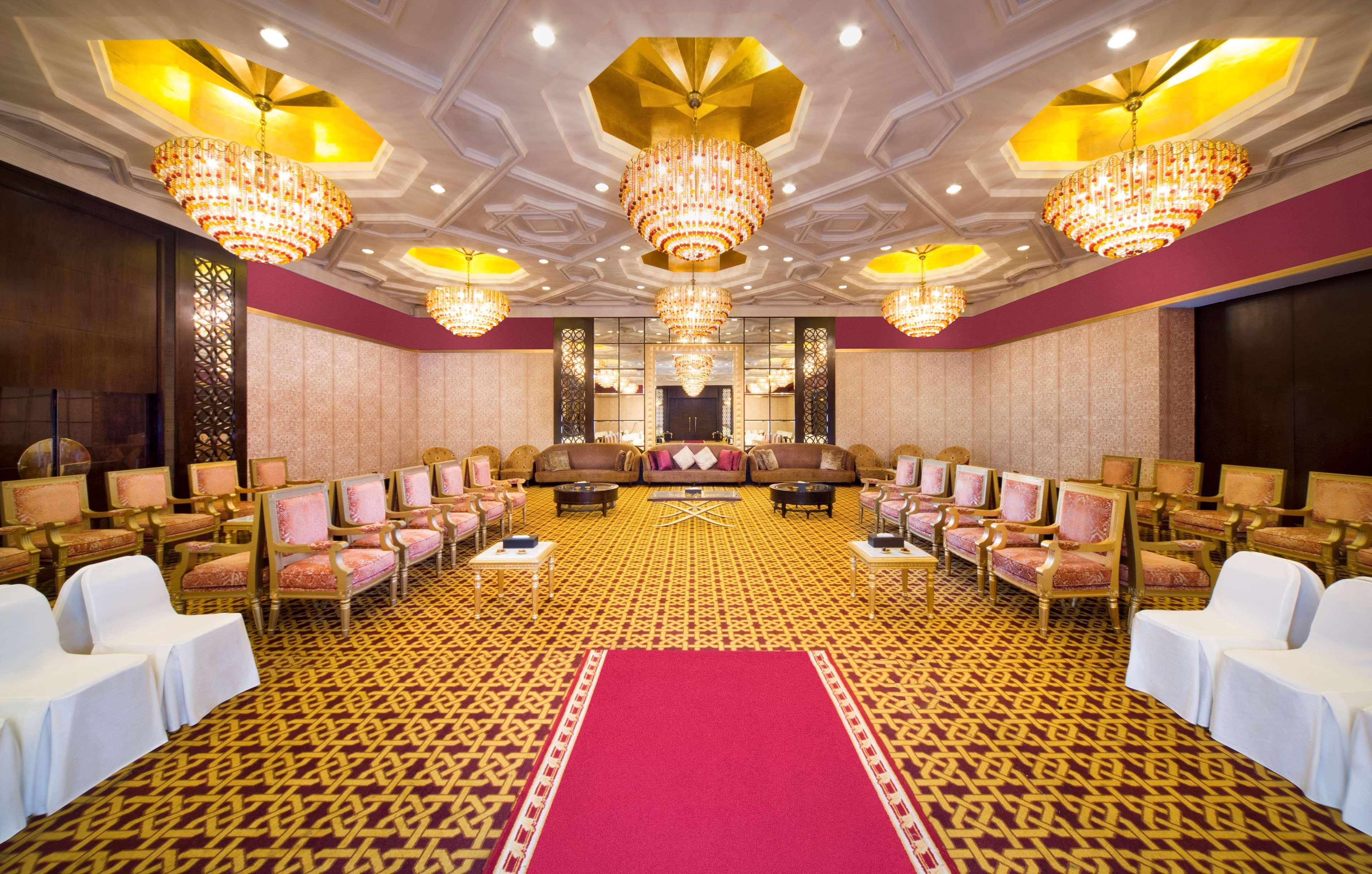 Radisson Blu Hotel & Resort, Abu Dhabi Corniche Extérieur photo The photo shows an elegantly designed interior space, likely a banquet or conference room. The room features ornate chandeliers with golden accents hanging from the ceiling, providing ample lighting. The walls are decorated with a subtle pattern, and