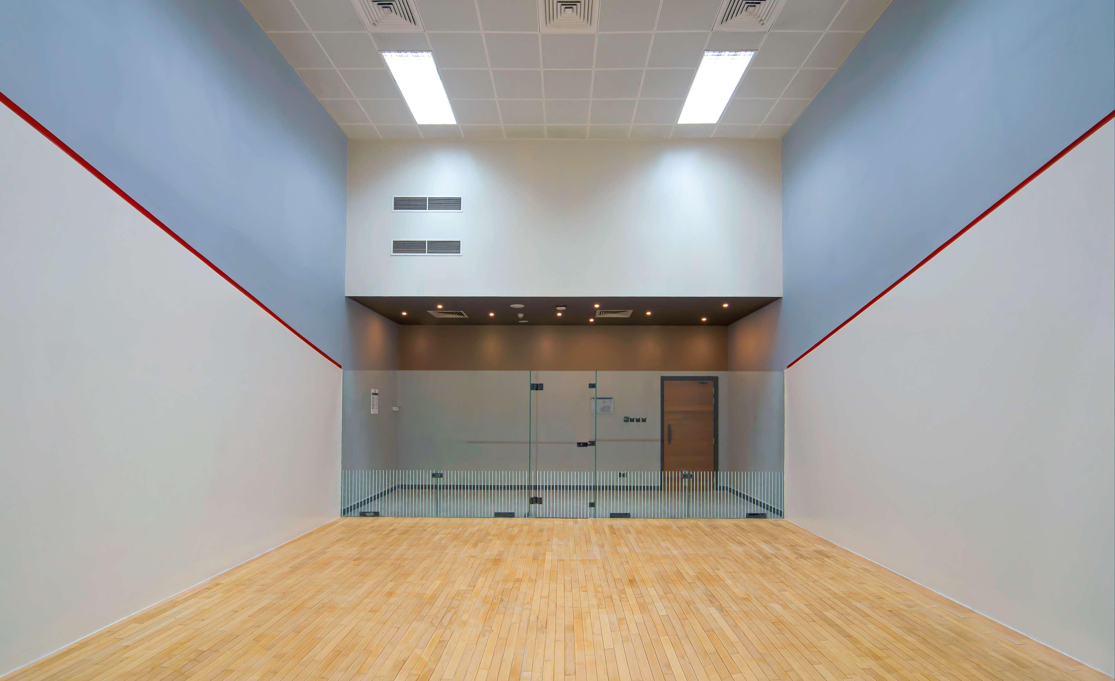 Radisson Blu Hotel & Resort, Abu Dhabi Corniche Extérieur photo The image shows an indoor squash court. The court has a wooden floor and four walls, two of which are painted white with a red line running horizontally at the height appropriate for the game. One wall features large glass panels, likely for viewing,