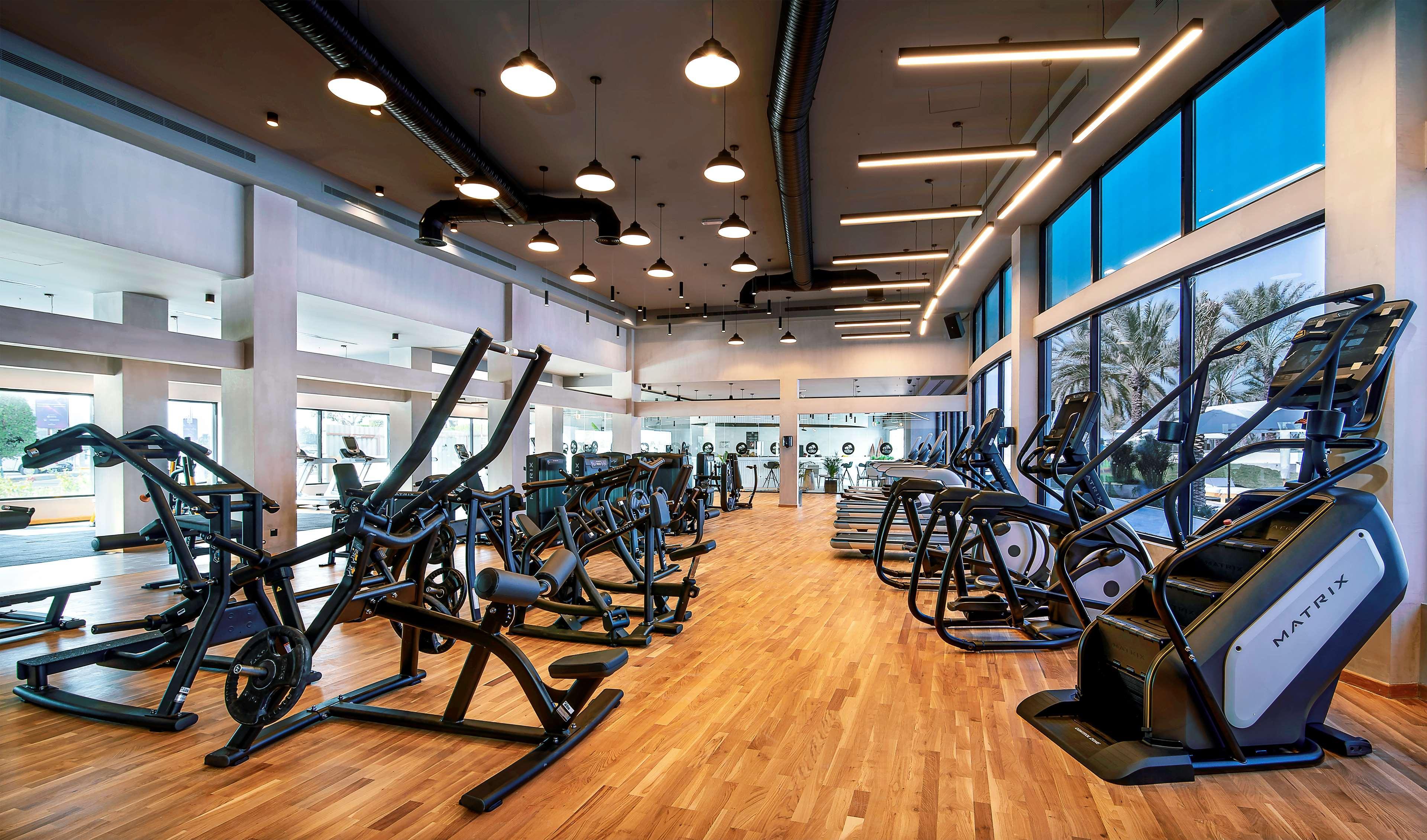 Radisson Blu Hotel & Resort, Abu Dhabi Corniche Extérieur photo The photo shows a modern gym or fitness area. It features a spacious layout with large windows that allow natural light to flood the space. The flooring is made of light-colored wood, giving the area a warm and inviting feel. 

Various pieces of exer