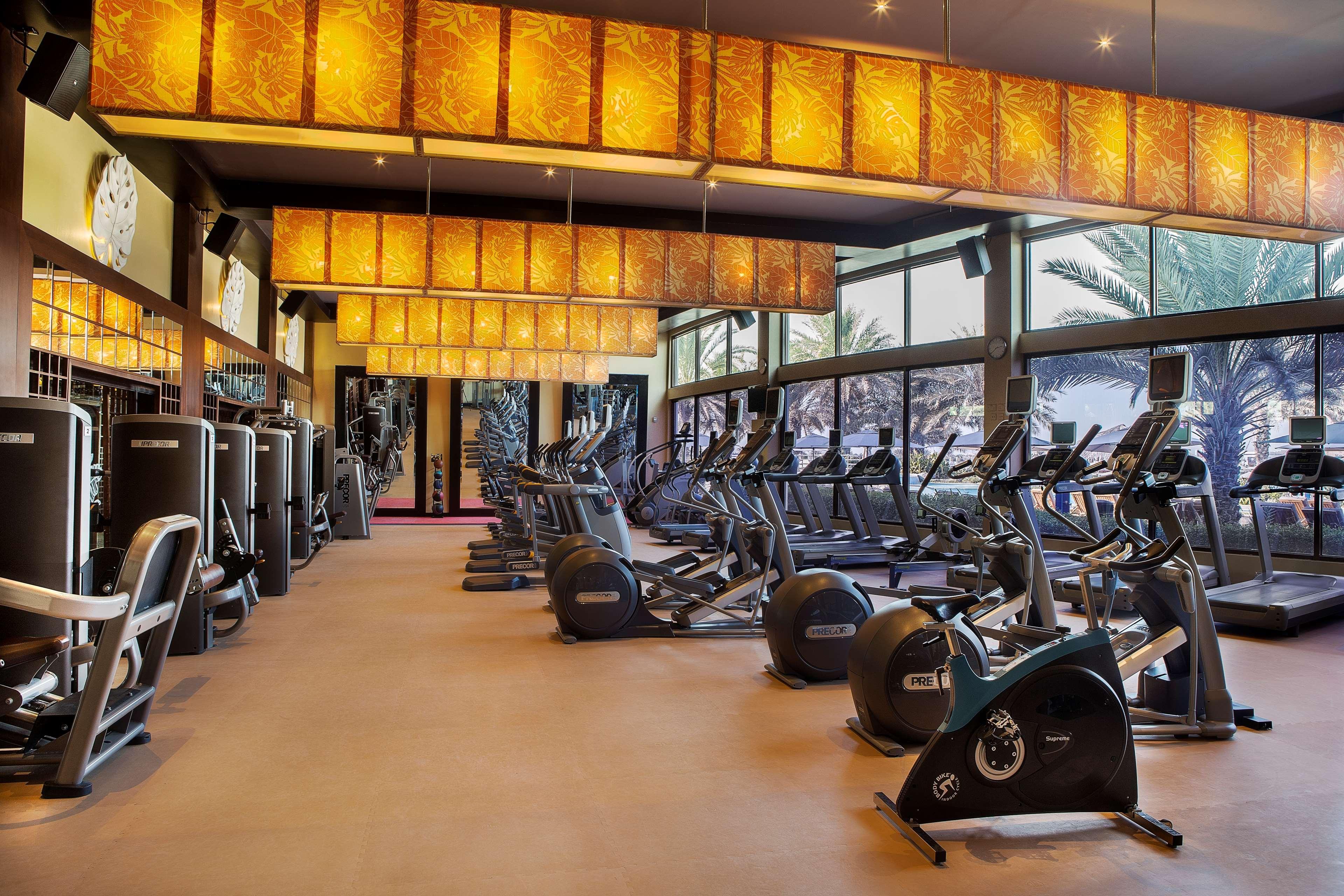 Radisson Blu Hotel & Resort, Abu Dhabi Corniche Extérieur photo The photo shows a modern gym interior with various exercise equipment. The gym features multiple cardio machines, such as treadmills and stationary bikes, arranged neatly. Large windows allow natural light to enter the space, and the walls are decora