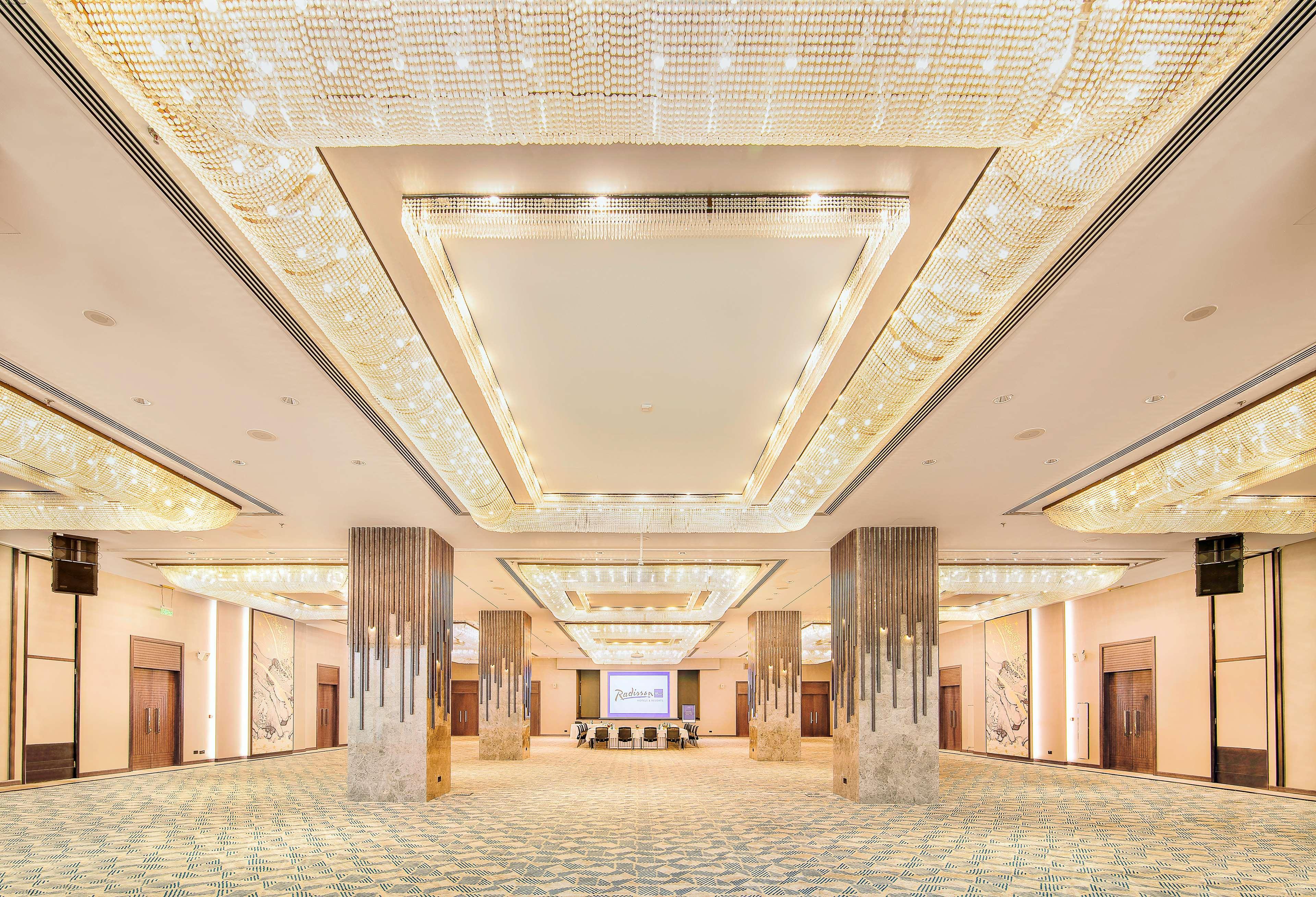 Radisson Blu Hotel & Resort, Abu Dhabi Corniche Extérieur photo The photo shows a spacious event hall with a luxurious design. The ceiling features an elaborate arrangement of lights, creating a bright and elegant atmosphere. The walls are adorned with decorative elements, and the floor appears to be covered with